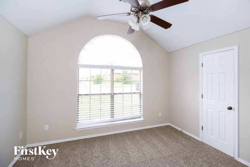 A room with a fan and a window with blinds.