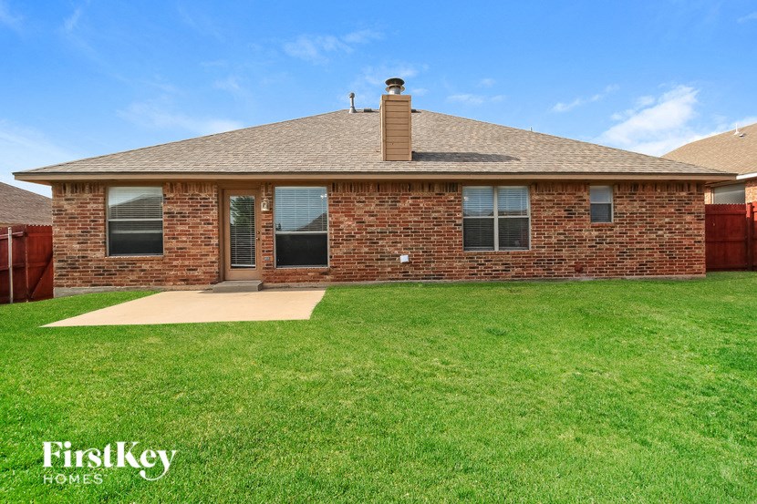 A brick house with a brown roof and a chimney.