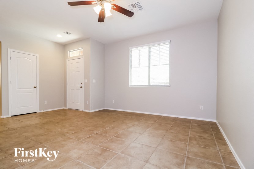 a empty living room with a ceiling fan and a white door