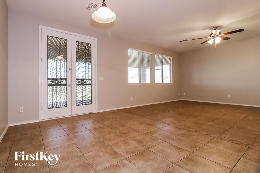 an empty living room with a ceiling fan and a window