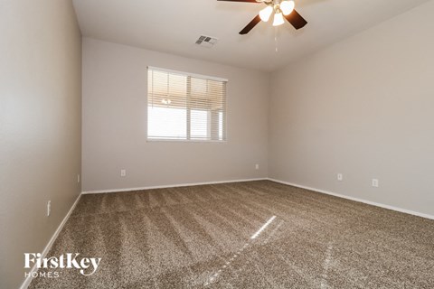 the spacious living room with carpet and a ceiling fan