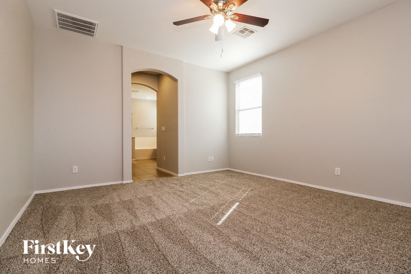 the spacious living room with carpet and ceiling fan