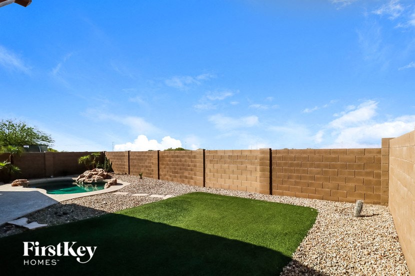 a backyard with artificial grass and a pool and a fence