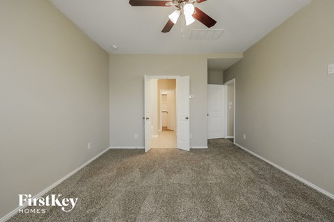 a spacious living room with carpet and a ceiling fan