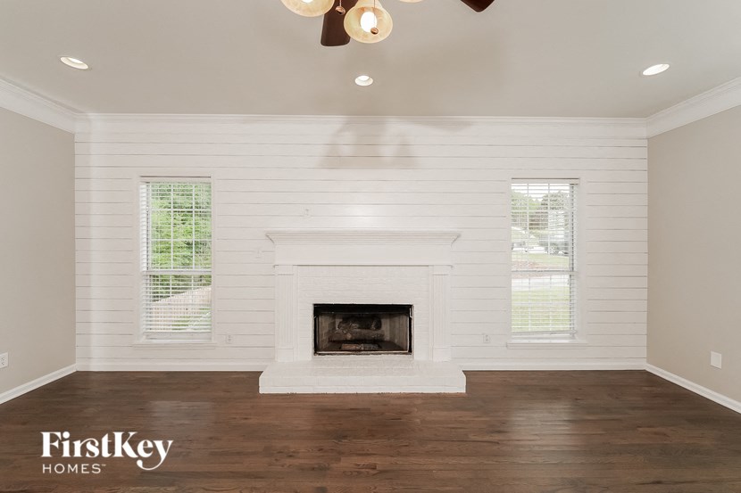 A well-lit room with a fireplace and wooden floors.