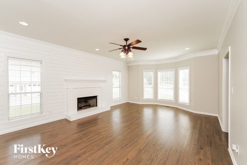 A spacious room with a fireplace and a ceiling fan.