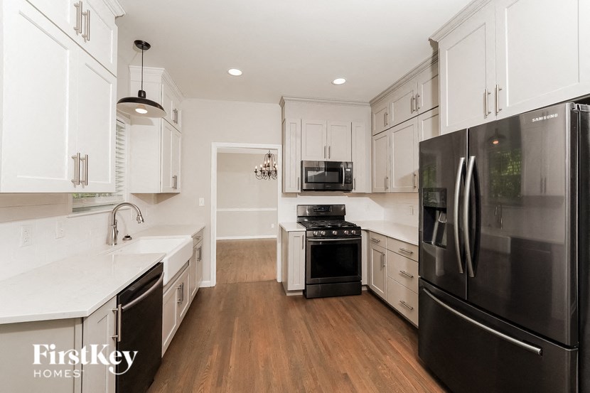 A modern kitchen with a black refrigerator and wooden floors.