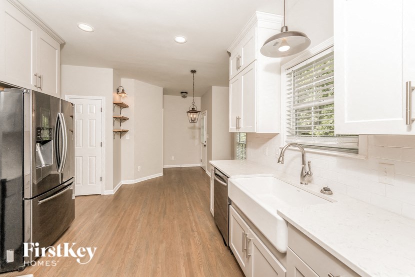A kitchen with white cabinets and a stainless steel refrigerator.