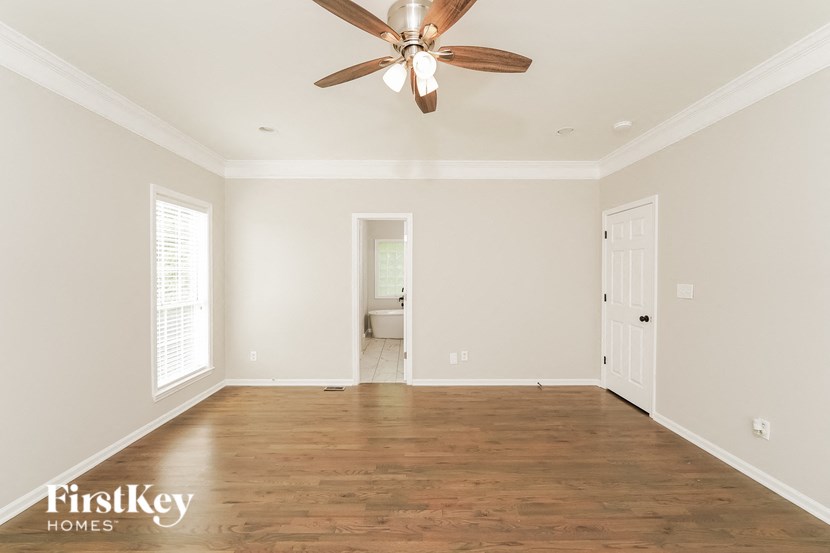 A spacious room with a ceiling fan and wooden flooring.