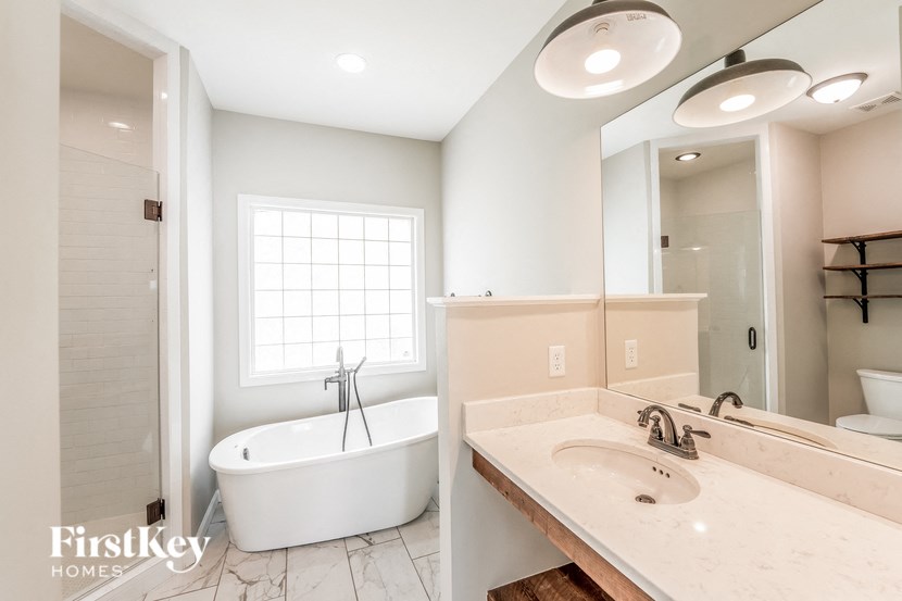 A white bathroom with a tub, sink, and mirror.