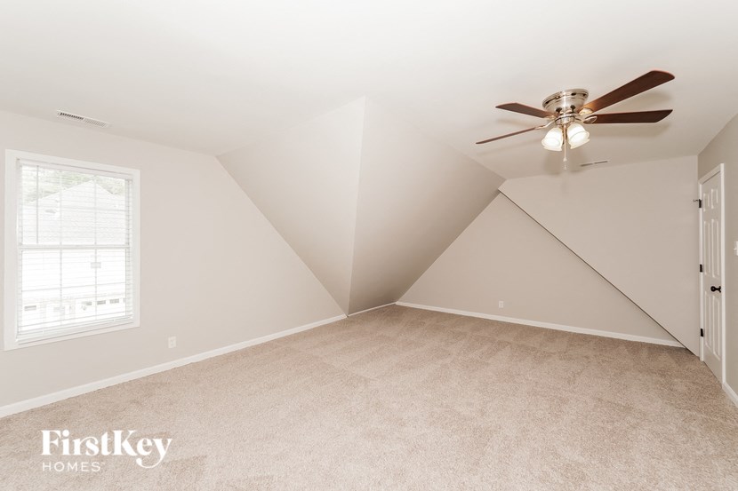 A spacious room with a ceiling fan and a window.