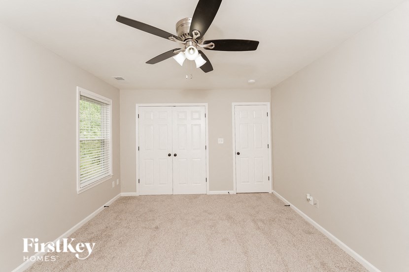 A room with a ceiling fan and two doors.