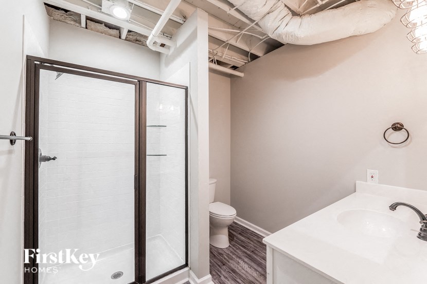 A white bathroom with a walk in shower and a toilet.