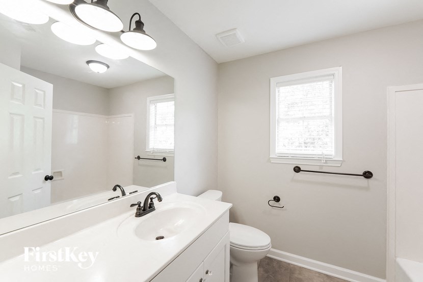 A white bathroom with a toilet, sink, and mirror.