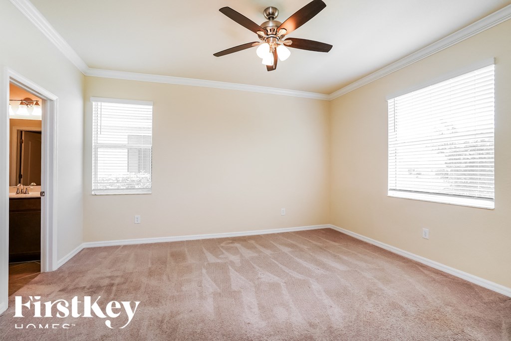 an empty room with a ceiling fan and two windows