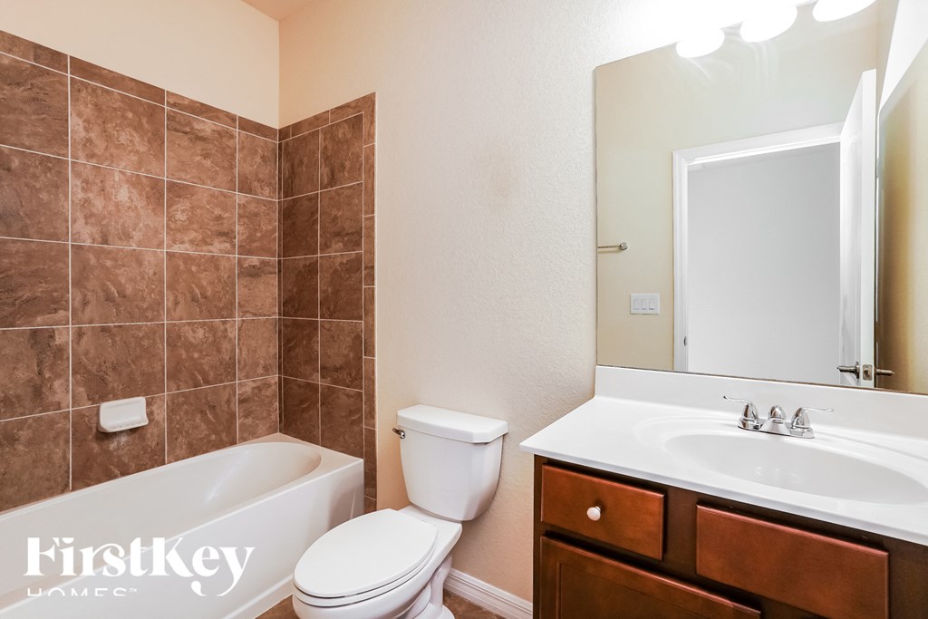 a bathroom with a toilet sink and tub and a mirror