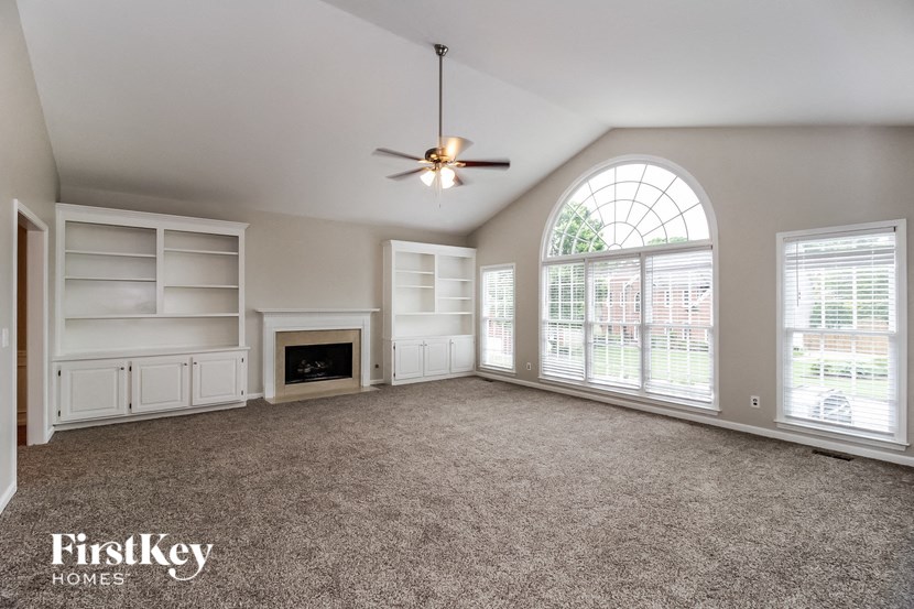an empty living room with a large window and a ceiling fan