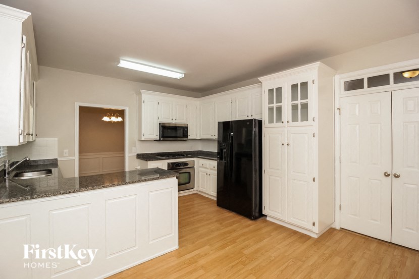 a kitchen with white cabinets and a black refrigerator