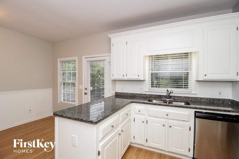 a white kitchen with granite counter tops and white cabinets