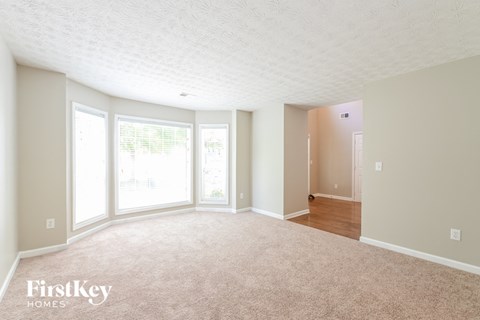 A spacious room with a carpeted floor and a doorway leading to another room.