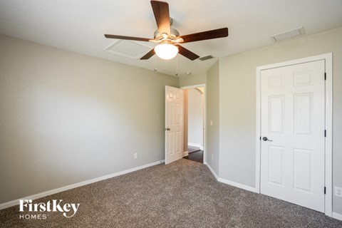 a bedroom with a ceiling fan and a door to a closet