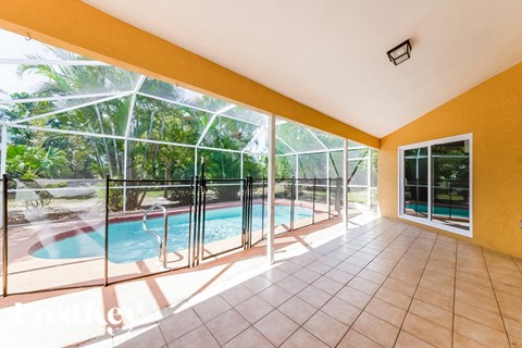 A sunny room with a pool and glass walls.