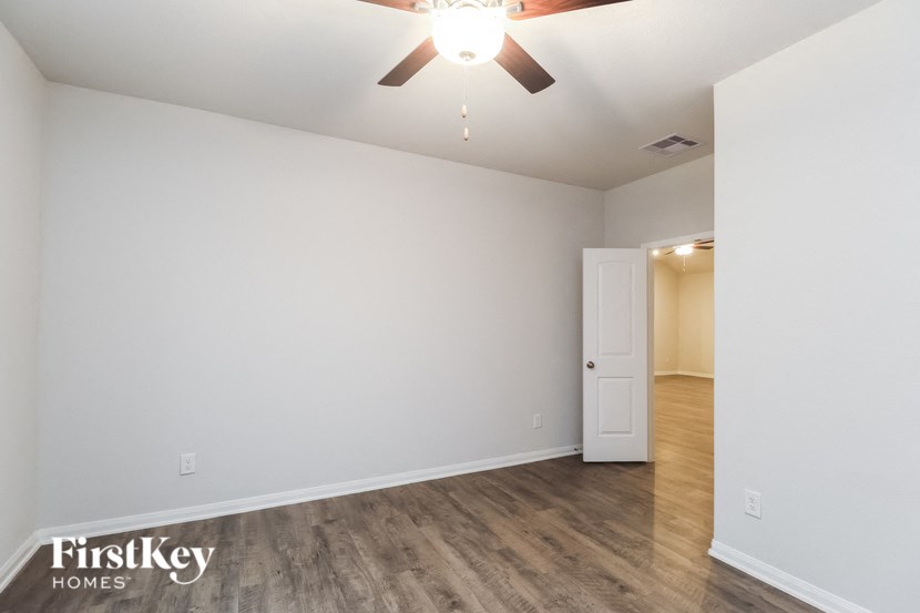 the living room of an apartment with a ceiling fan and white walls
