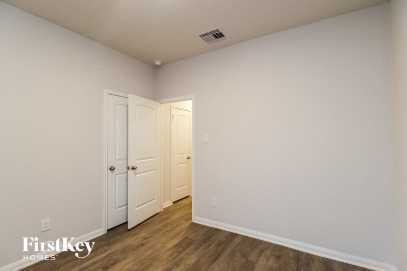 a bedroom with white walls and wooden floors and two doors