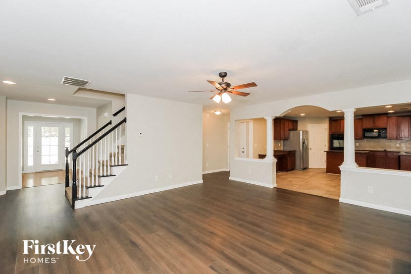 an empty living room with a ceiling fan and a staircase