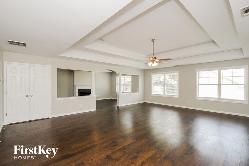 an empty living room with wood floors and a ceiling fan