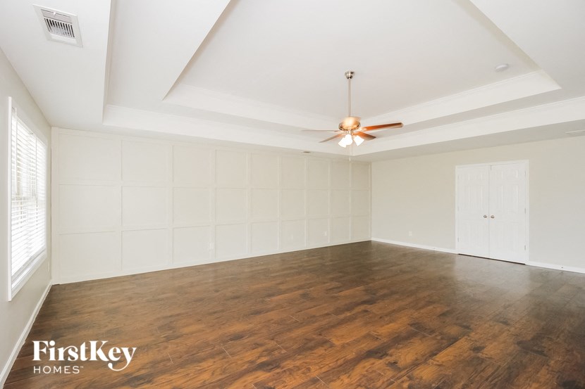 an empty living room with white walls and a ceiling fan
