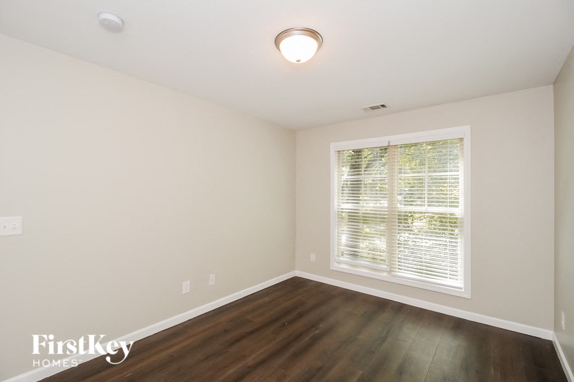 the living room of an empty home with a large window and wooden floors