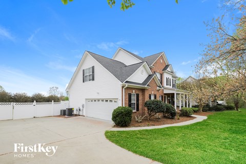 a white house with a driveway and a white fence