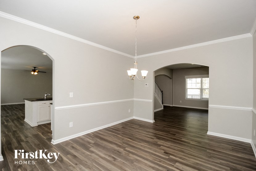A spacious room with wooden floors and a chandelier hanging from the ceiling.