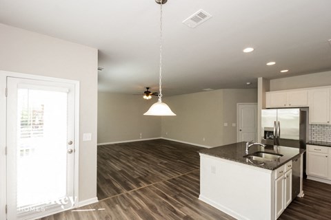 A modern kitchen with a large island and wooden flooring.