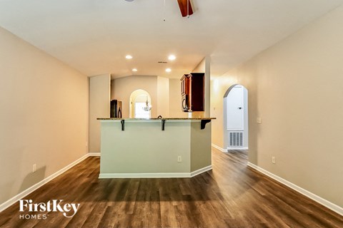 A spacious room with a wooden floor and a bar area.