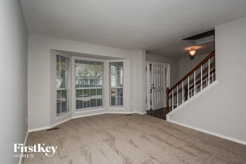 an empty living room with large windows and a staircase