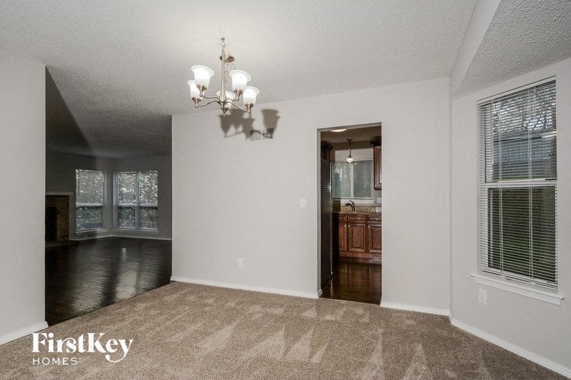 an empty living room with a window and a door to a kitchen