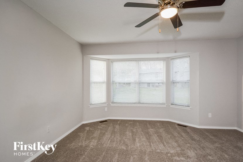 a living room with a ceiling fan and three windows