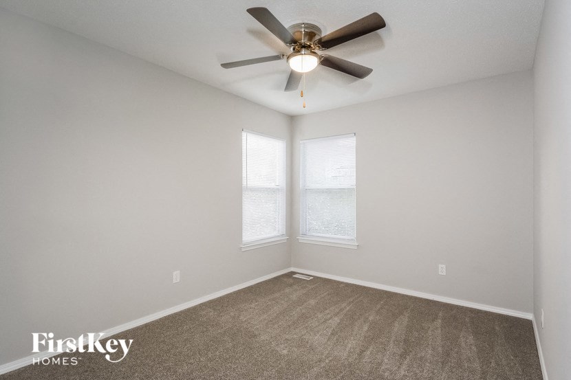 the living room has a ceiling fan and two windows