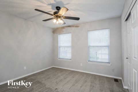 a bedroom with two windows and a ceiling fan