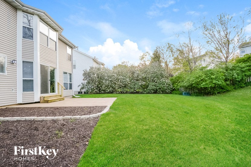 a backyard with a green lawn and a white house