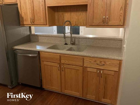 A kitchen with wooden cabinets and a stainless steel refrigerator.
