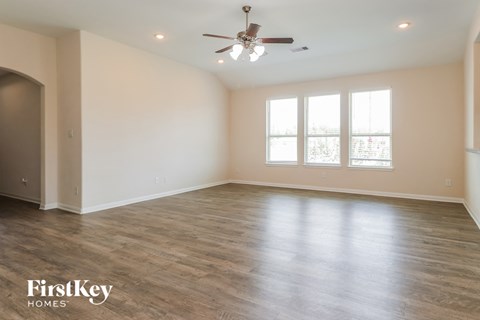 the spacious living room with wood flooring and a ceiling fan