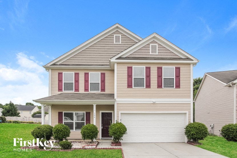 a beige house with red shutters and a driveway