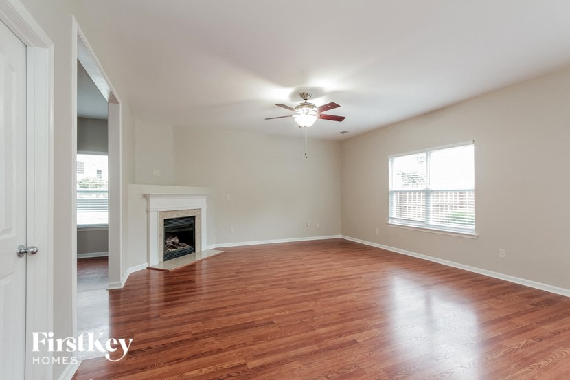 an empty living room with a ceiling fan and a fireplace