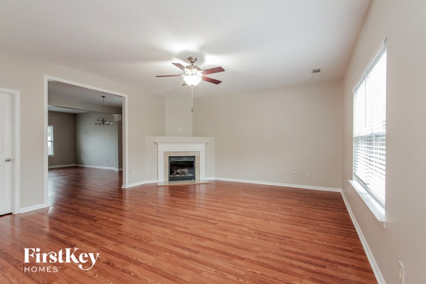 an empty living room with a ceiling fan and a fireplace