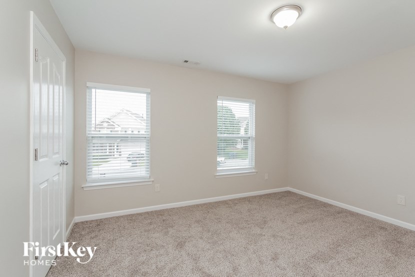 an empty bedroom with two windows and a door