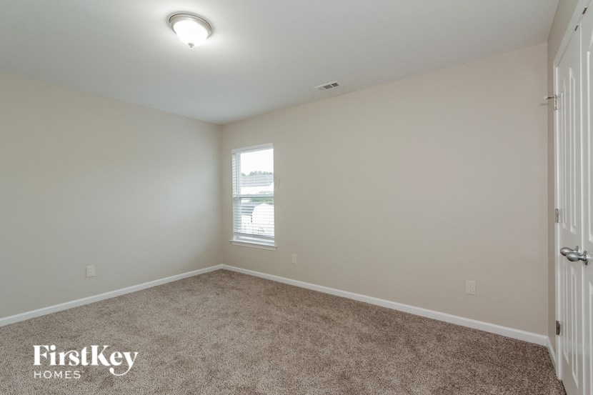 an empty bedroom with a window and carpeting