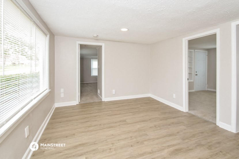 an empty living room with a wooden floor and a large window